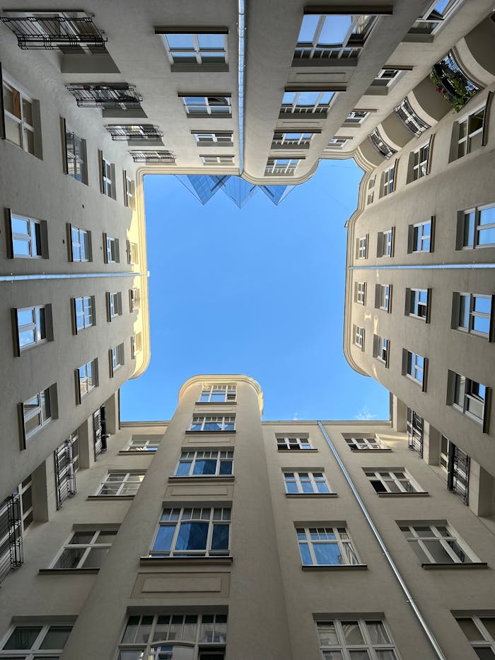 Upward view of a symmetrical urban courtyard with a clear blue sky visible above.
